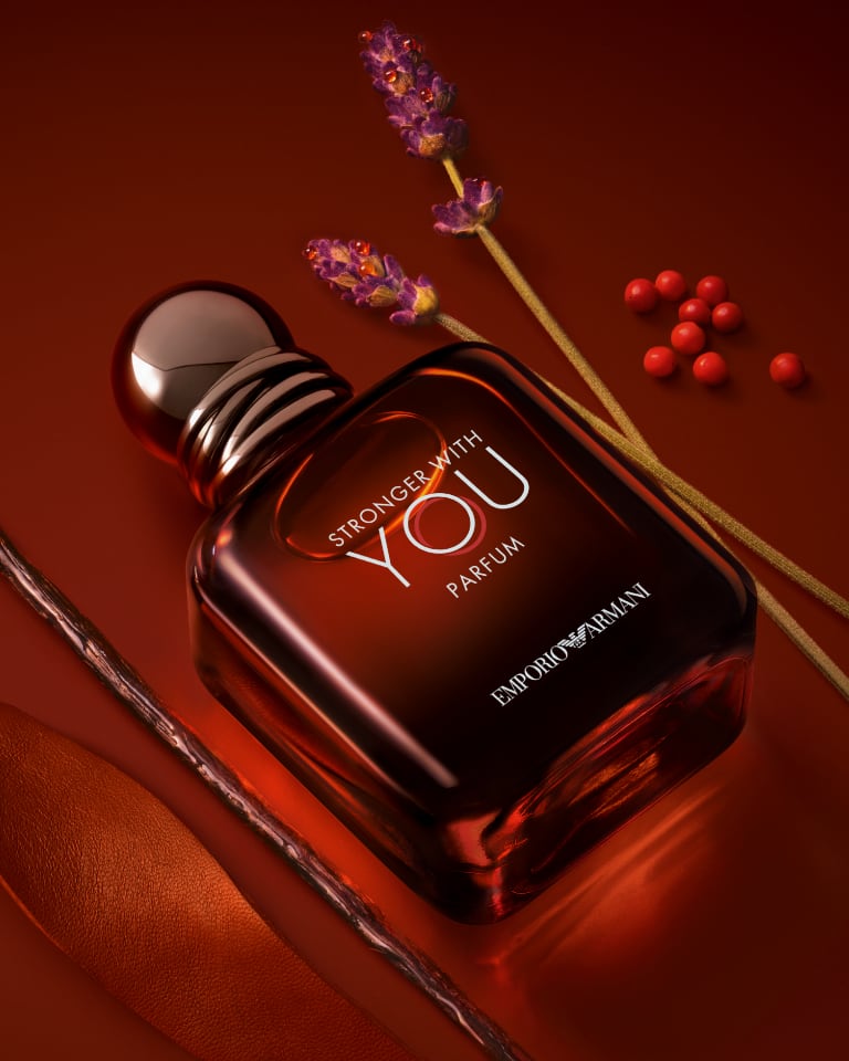 Photographs of three Giorgio Armani Sì fragrance bottles in three different formats against a red background